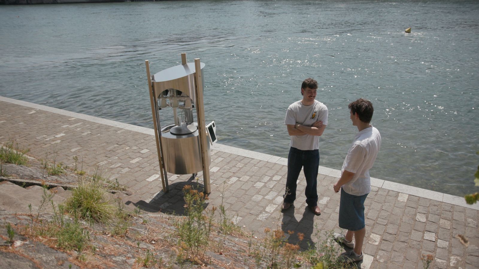 Two visitors standing next to the robot on the Rhine promenade.